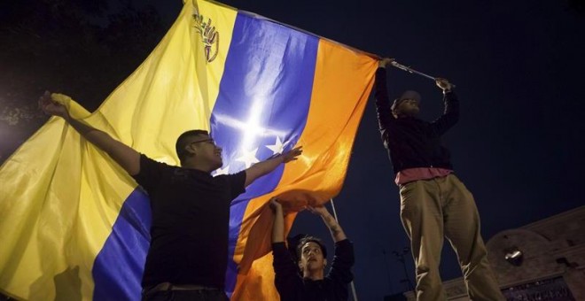 Un grupo de personas celebra la victoria obtenida por la coalición opositora Mesa de Unidad Democrática (MUD) este lunes en Caracas./ EFE