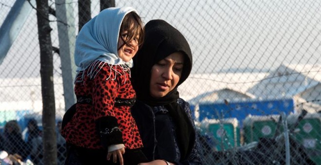 Una mujer carga a su bebé mientras se dirige al centro de registro de migrantes tras cruzar la frontera entre Macedonia y Grecua, en Macedonia. EFE