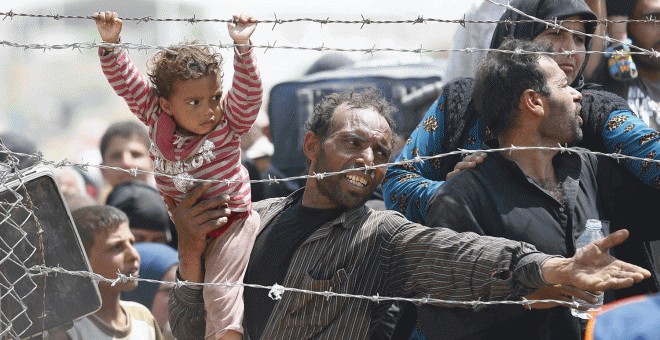 Un hombre sirio y su hija en la frontera con Turquía. REUTERS