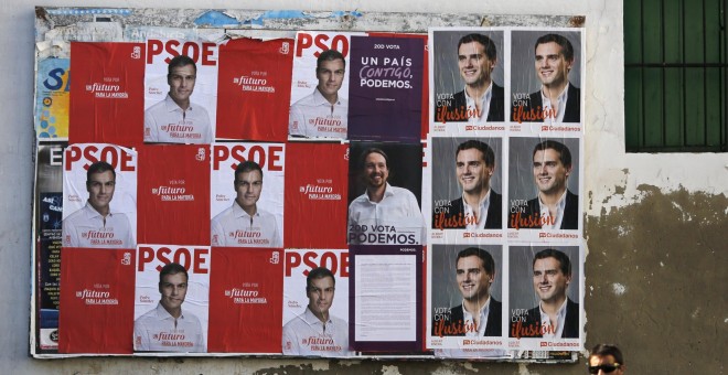 Un hombre camina delante de varios carteles del PSOE, Podemos y C`s, en Sanlúcar de Barrameda, Cádiz. REUTERS/Marcelo del Pozo