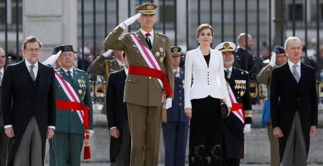 Los reyes, junto al presidente del Gobierno, Mariano Rajoy (i), y el ministro de Defensa, Pedro Morenés (d), escuchan el himno nacional durante la celebración de la Pascua Militar, a la que asisten representantes de las instituciones del Estado, los tres