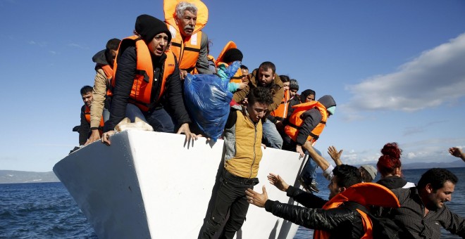 Refugiados y emigrantes saltan de un barco al llegar a la isla griega de Lesbos, en una foto de archivo./REUTERS