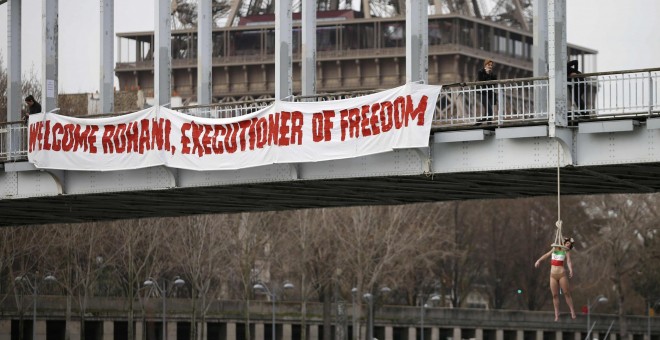 Una activista de Femen, congada de un puente de París cerca de la Torre Eiffel, para protestar contra el régimen iraní, con motivo de la visita de su presidente  Hassan Rohani. REUTERS/Charles Platiau