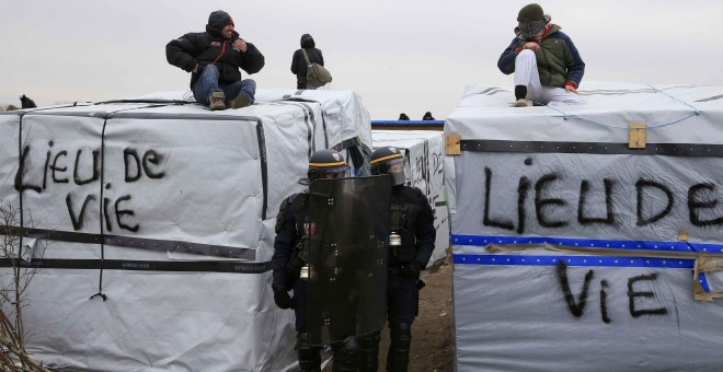 Agentes antidisturbios pasan entre los refugios levantados en la 'Jungla' de Calais. - REUTERS