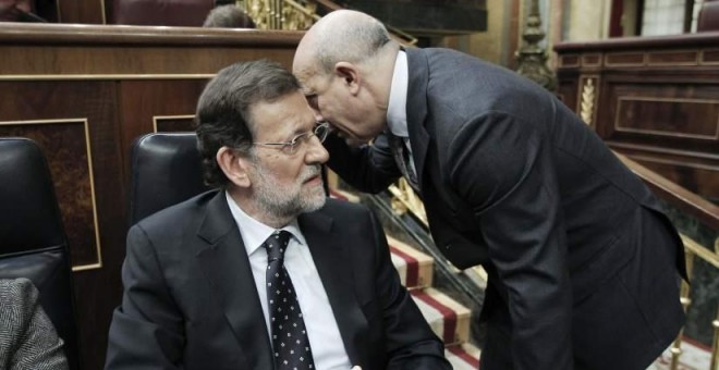 Mariano Rajoy escucha una confidencia del entonces ministro de Educación, José Ignacio Wert, en un debate de Presupuestos en el Congreso de los Diputados. EFE