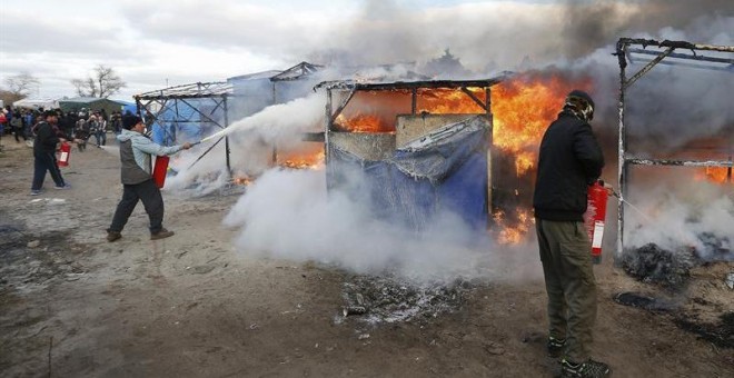 Varias personas tratan de apagar el incendio de uno de los refugios del campamento. - EFE