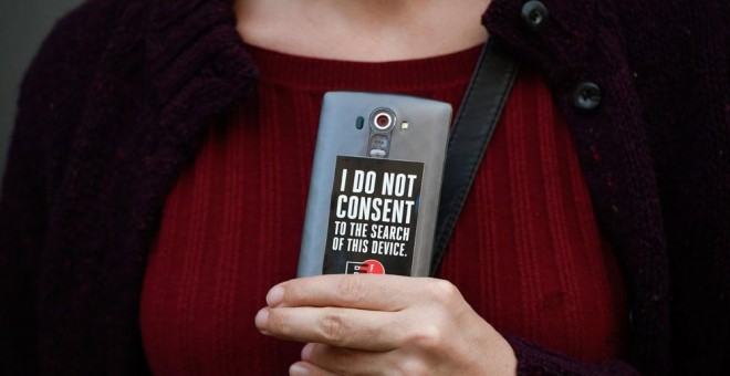 Una mujer sostiene su teléfono con una pegatina en la que se puede leer 'No consiento la inspección de este móvil' durante una manifestación en apoyo a Apple en San Francisco. EFE