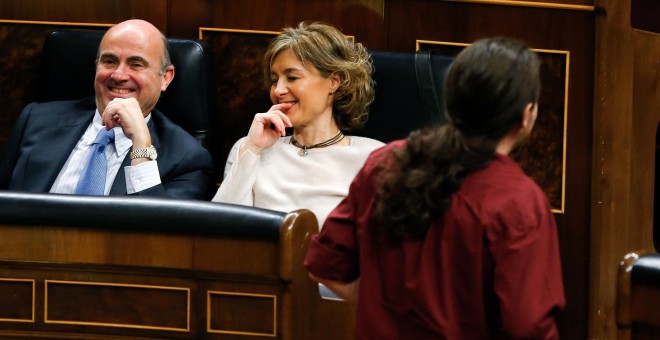 El líder de Podemos, Pablo Iglesias (d), pasa junto a los ministros en funciones de Economía, Luis de Guindos (i), y de Agricultura, Isabel García Tejerina. EFE/Ballesteros