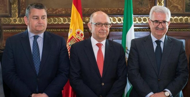 El ministro de Hacienda, Cristóbal Montoro (c), acompañado por el presidente del PP de Cádiz, Antonio Sanz (i), y el vicepresidente de la Junta de Andalucía, Manuel Jiménez Barrios (d), durante el acto de constitución de la Comisión Nacional de Coordinac