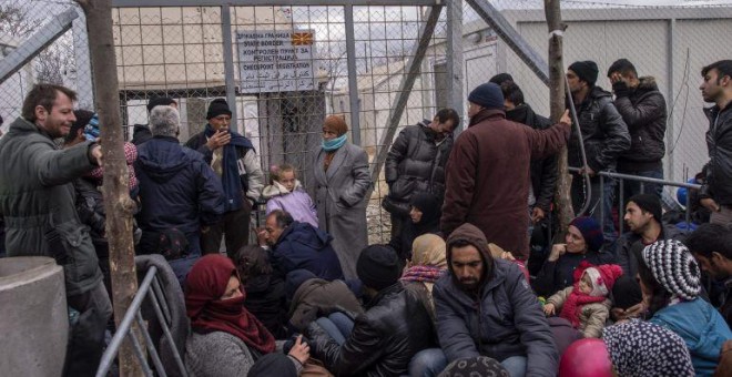 Varios refugiados esperan junto al paso fronterizo a poder entrar en Macedonia desde Grecia cerca de la localidad helena de Idomeni. EFE/Georgi Licovski