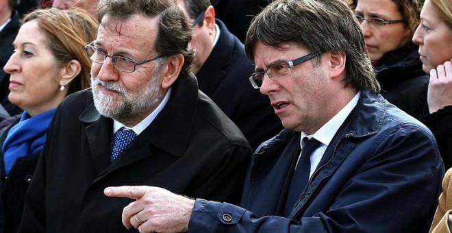 El jefe del Ejecutivo, Mariano Rajoy, y el presidente de la Generalitat, Carles Puigdemont (d), encabezan el acto de homenaje a las víctimas del accidente del vuelo Germanwings 9525, celebrado hoy en el aeropuerto de El Prat en la víspera del primer anive