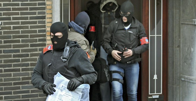 Policías enmascarados sacan objetos de un edificio de Anderlecht durante uno de sus registros tras los atentados. - REUTERS