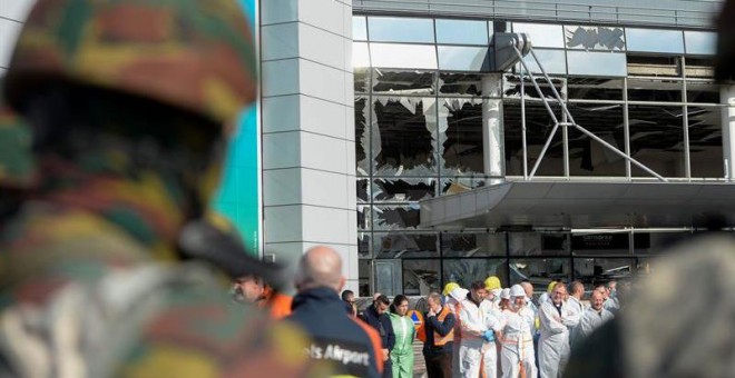 Varios operarios guardan un minuto de silencio en memoria de las víctimas en el aeropuerto de Bruselas-Zaventem, Bélgica.- Frederic Sierakowski (EFE)