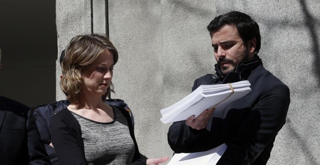 El portavoz de IU en el Congreso, Alberto Garzón, y la eurodiputada Marina Albiol muestran la querella que han presentado en el Tribunal Supremo contra el presidente del Gobierno en funciones, Mariano Rajoy, por un presunto delito de 'crímenes de lesa hum