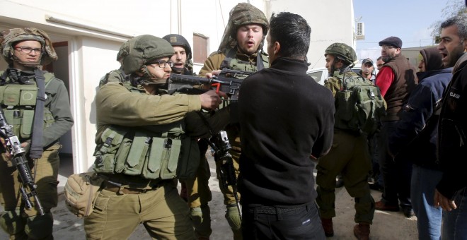 Un soldado israelí apunta con su arma a un grupo de palestinos en Nablús. - REUTERS