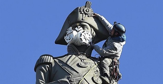 Un activista de Greenpeace coloca una mascarilla a la estatua de Nelson en la plaza de Trafalgar en Londres durante las protestas contra la polución. EFE