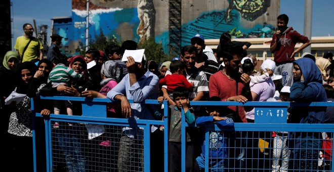 Refugiados y migrantes esperan a subir un autobús que les traslade de El Pireo a un centro organizado por el Gobierno griego. - REUTERS
