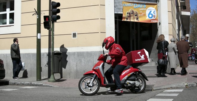 Un repartidor de Telepizza, con su moto, en un establecimiento de Madrid. REUTERS