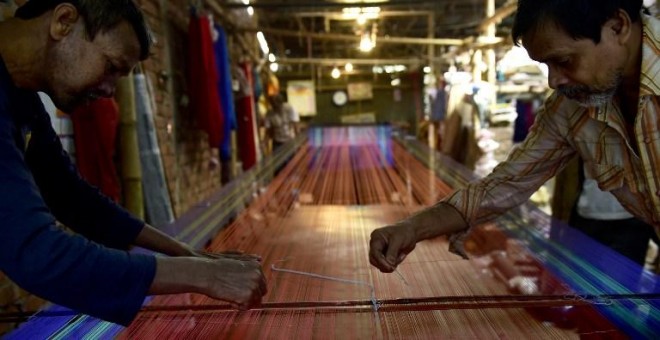 Dos tejedores trabajan en una fábrica de telas en Dacca. - AFP