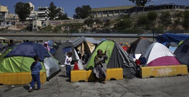 Una refugiada repara su tienda de campaña en el campamento improvisado en el puerto del Pireo, Atenas. - EFE