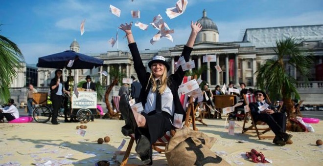 Una mujer lanza billetes al aire en una protesta contra los paraísos fiscales en la plaza Trafalgar de Londres. EFE/Hannah Mckay