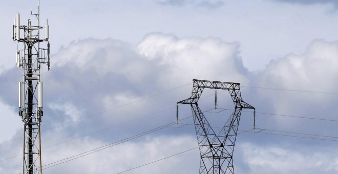 Una torre de alta tensión junto a una antena de telefonía móvil. REUTERS