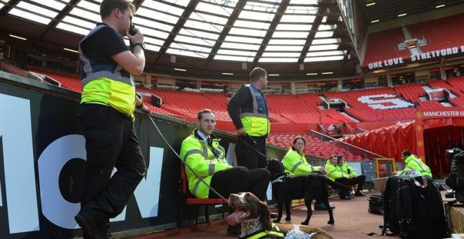 Varios agentes de seguridad y un perro en el interior del estadio Old Trafford tras evacuarlo. /EFE