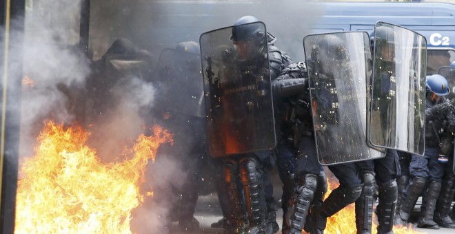 Gendarmes franceses, entre llamas provocadas por un grupo de encapuchados en París, durante las protestas contra la reforma laboral.- REUTERS