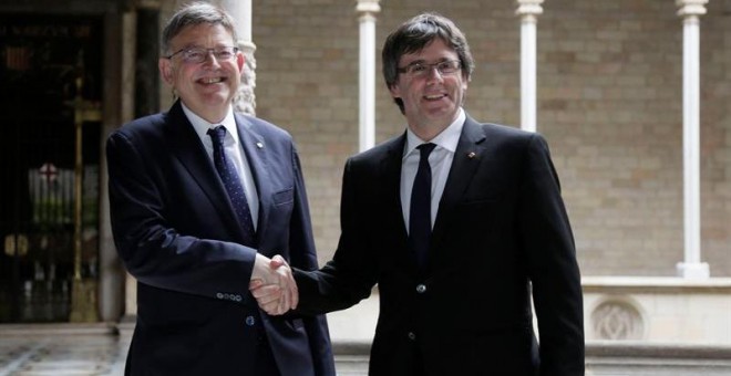 El presidente de la Generalitat, Carles Puigdemont (d), recibe al presidente de la Generalitat Valenciana, Ximo Puig (i) al inicio de la reunión que ambos mandatarios mantuvieron en el Palau de la Generalitat.