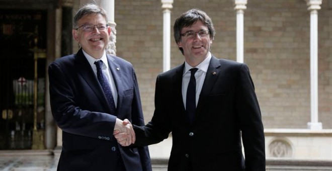 El presidente de la Generalitat, Carles Puigdemont (d), recibe al presidente de la Generalitat Valenciana, Ximo Puig (i) al inicio de la reunión que ambos mandatarios mantuvieron en el Palau de la Generalitat.