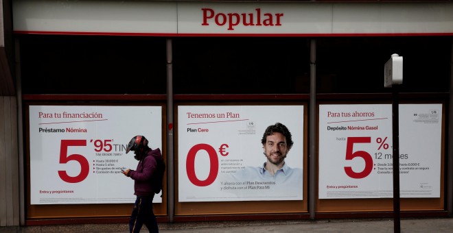 Un hombre con un casco de motorista pasa por delante de una sucursal del Banco Popular eb Madrid. REUTERS/Susana Vera