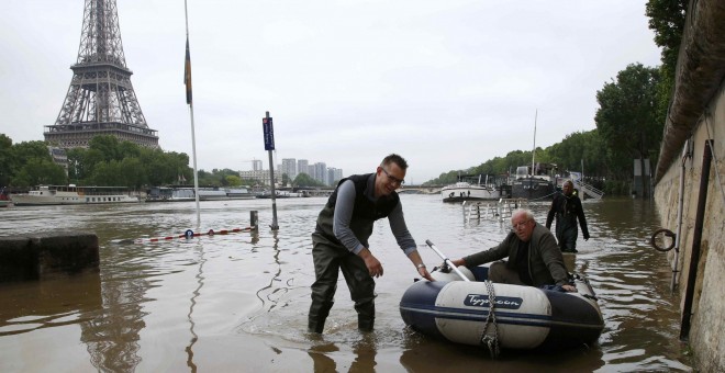 Un hombre utiliza un bote para salir de su casa flotante amarrada cerca de la torre Eiffel durante la inundación provocada por la crecida del río Sena en París , Francia.- REUTERS / Pascal Rossignol