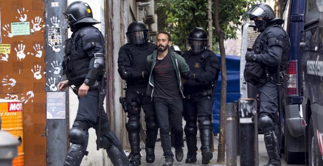 Los Mossos d'Esquadra custodian a uno de los okupas detenidos que han vuelto a entrar en el llamado 'Banc Expropiat' del barrio barcelonés de Gràcia. EFE/Quique García