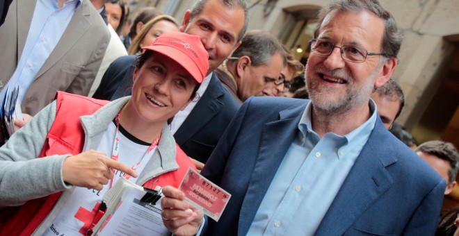 El presidente del Gobierno en funciones y candidato del PP, Mariano Rajoy, con una vendedora de la lotería de la Cruz Roja, en su paseo por Pontevedra antes de un acto de la campaña del 26-J. REUTERS/Miguel Vidal