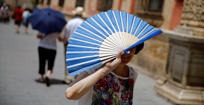 Una mujer se cumbre del sol con su abanico en una calle de  Sevilla. REUTERS/Marcelo del Pozo