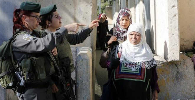 Miembros de la seguridad israelí chequean a unas mujeres musulmanas mientras cruzan la zona de control de Israel a las afueras de la ciudad cisjordana de Belén. - EFE