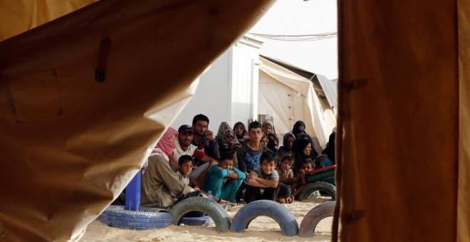 Refugiados sirios esperan para subir a un vehículo militar de Jordania tras conseguir cruzar la frontera norte entre ambos países con sus familias. REUTERS/Muhammad Hamed