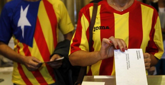 Una ciudadana deposita su voto en una mesa de en un colegio electoral de Barcelona durante el referéndum que tuvo lugar el 9-N del año 2014.- EFE