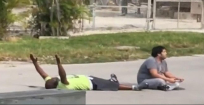 Captura del vídeo que muestra el momento en que el terapeuta se encuentra tumbado en el asfalto con las manos en alto frente a la Policía junto a su paciente con autismo