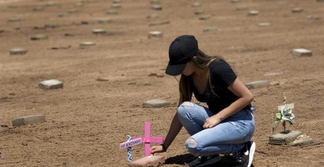 Una estudiante de una clase de bachillerato de Denver (Colorado) coloca una cruz junto a unos ladrillos de cemento que marcan el lugar donde está enterrada una persona sin identificar en cercanías al cementerio Terrace Park en Holtville, en medio del desi