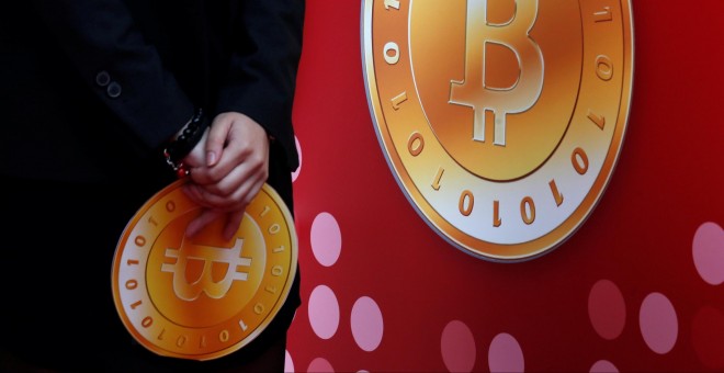 Un empleado de la tienda bitcoin de Hong Kong sostiene el logo de la moneda virtual. REUTERS/Bobby Yip