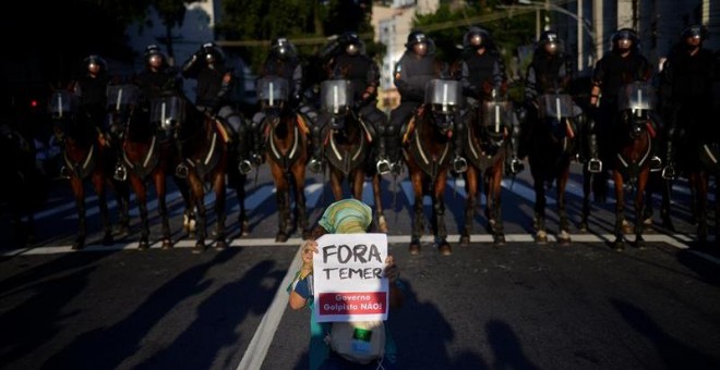 Policías brasileños y un manifestante con una pancarta en la que se reza "Fuera Temer", durante una protesta contra los Juegos Olímpicos. EFE/FAVIO TEIXEIRA