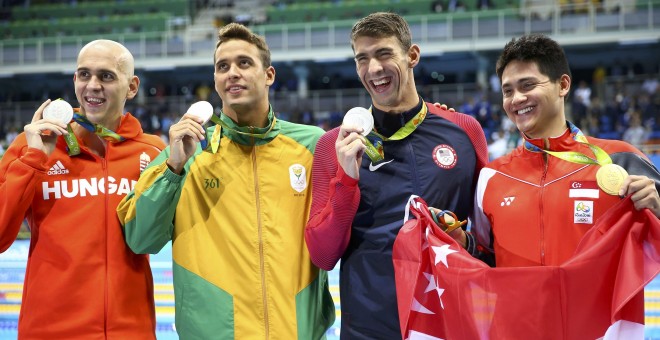 De izquierda a derecha, los nadadores Laszlo Cseh (Hundría), Chad Le Clos (Sudáfrica) y Michael Phelps (EEUU), con su medalla de plata en la final de 100 mariposa, junto al medalla de oro, Joseph Schooling (Singapur). REUTERS/Michael Dalder