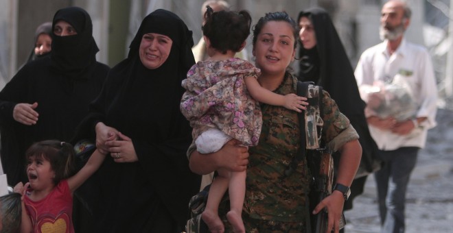 Una combatiente de las Fuerzas Democráticas de Siria evacúa a los civiles tras la victoria sobre el Estados Islámico en la ciudad siria de Manbyi.- REUTERS/Rodi Said