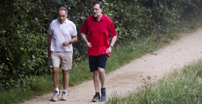 El presidente del Gobierno en funciones, Mariano Rajoy, acompañado de José Benito Suárez, presidente de la Autoridad Portuaria de Marín y marido de la presidenta del Congreso, Ana Pastor, en su paseo matutino por la Ruta del Agua y la Piedra, en la zona d