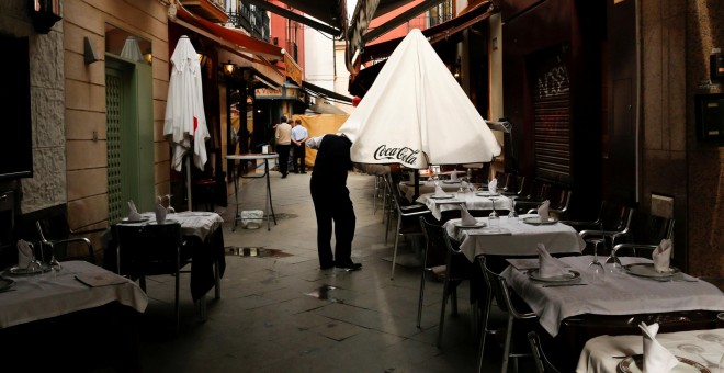 Un camarero abre una sombrilla en una terraza de un bar en Sevilla. REUTERS