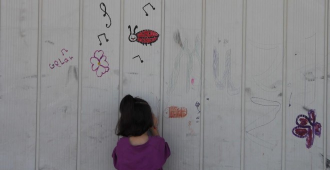 Una niña dibuja en una pared del campo de Sindos, en los alrededores de Tesalónica. - TOMÁS PARRA