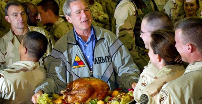 El expresidente de EEUU, George W. Bush, posa para una foto portando un pavo de Acción de Gracias durante su visita a las topas estadounidenses en Bagdad, el 27 de noviembre de 2003. El pavo resultó ser una recreación falsa de plástico.- TIM SLOAN (AFP)