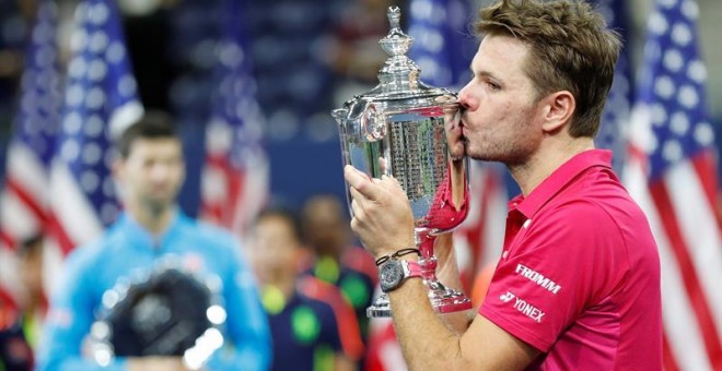 El suizo Stanis Wawrinka besa la copa de campeón del US Open con Djokovic de fondo. /EFE