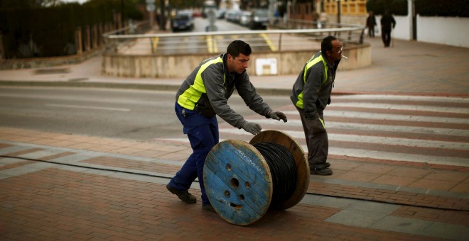 Dos trabajadores trasladan un rodillo de cable eléctrico en la localidad malagueña de Ronda. REUTERS / Jon Nazca